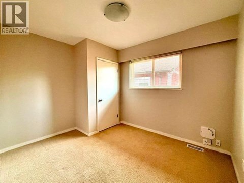 A room with a carpeted floor and a window with blinds.
