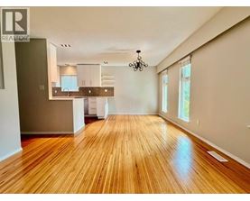 A large open room with wooden floors and a kitchen area in the background.