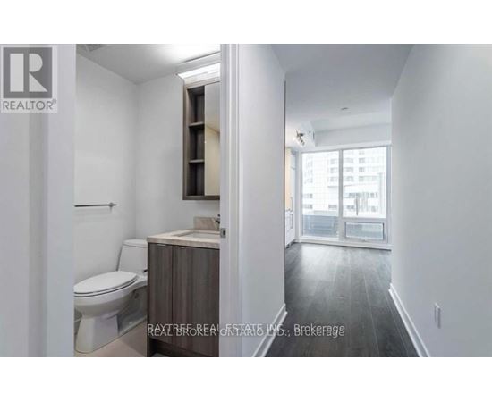 A bathroom with a toilet, sink, and a window.