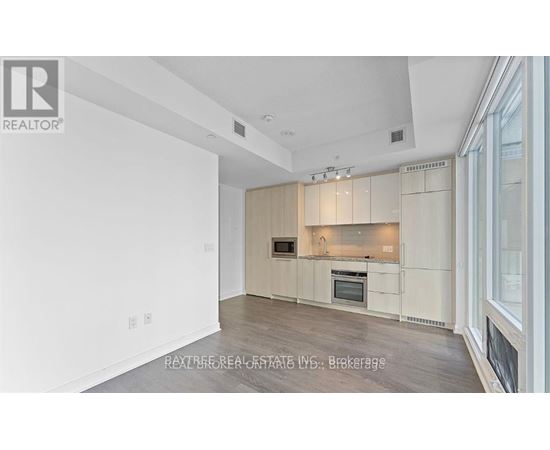 A spacious kitchen with white cabinets and a wooden floor.