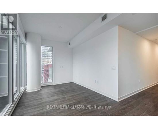 A spacious room with wooden flooring and white walls.