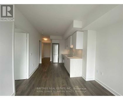 A real estate company logo is displayed on a wall in a spacious, empty room.