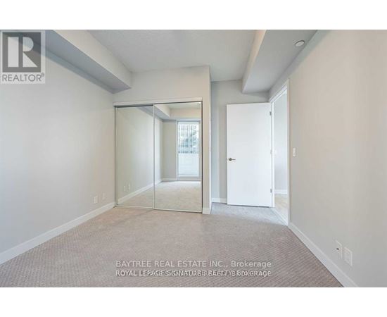 A real estate listing image of a room with a carpeted floor and a sliding glass door.
