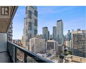 A cityscape with a clear blue sky and a building with a balcony in the foreground.