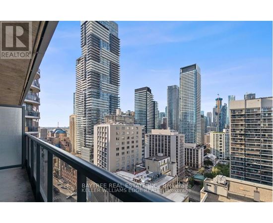 A cityscape with a clear blue sky and a building with a balcony in the foreground.