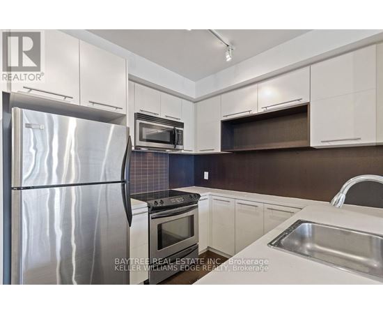 A modern kitchen with a stainless steel refrigerator and white cabinets.