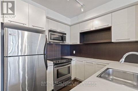 A modern kitchen with a stainless steel refrigerator and white cabinets.