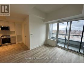 A spacious room with a large window overlooking a parking lot.