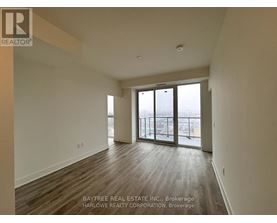 A spacious room with wooden flooring and sliding glass doors leading to a balcony.