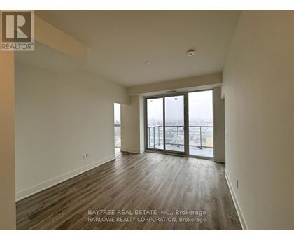 A spacious room with wooden flooring and sliding glass doors leading to a balcony.