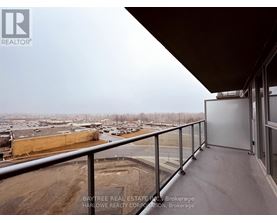 A balcony with a view of a parking lot and buildings.