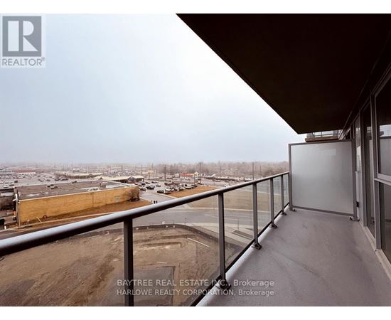 A balcony with a view of a parking lot and buildings.