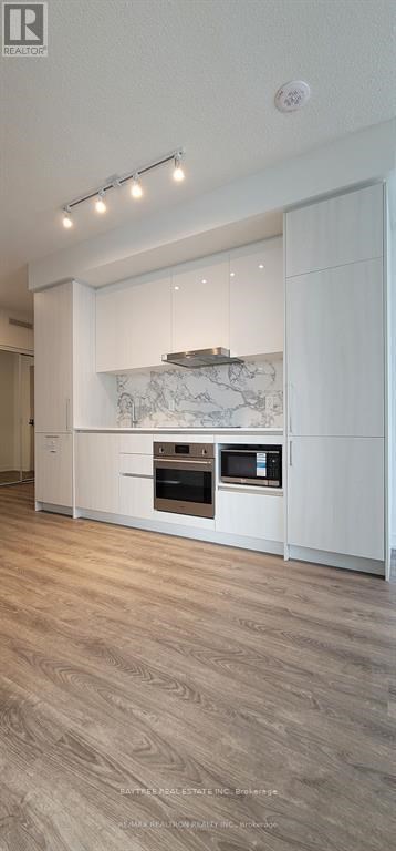 A modern kitchen with a marble backsplash and wooden flooring.