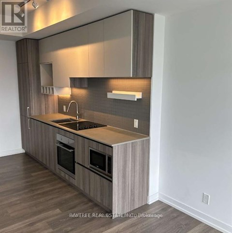 A modern kitchen with wooden cabinets and a dark countertop.
