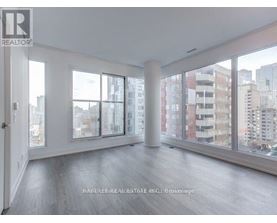 A spacious room with large windows and wooden flooring.