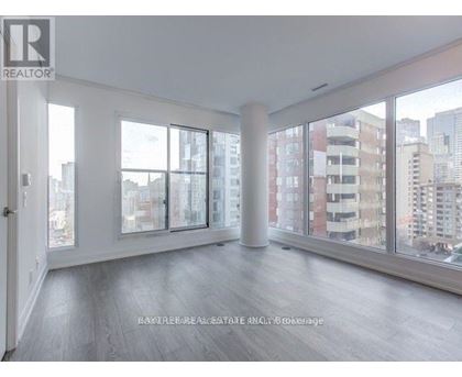 A spacious room with large windows and wooden flooring.
