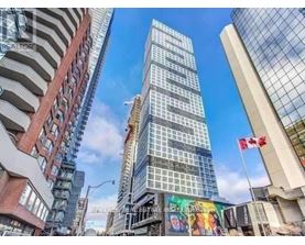 A tall glass building stands in the middle of a city street.