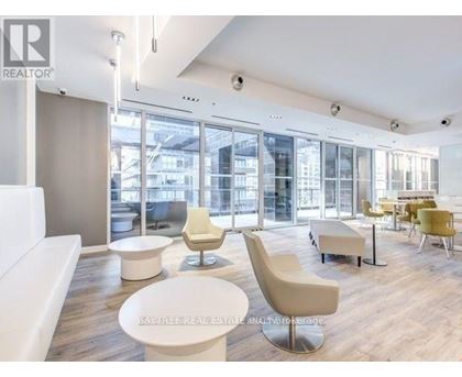 A modern living room with white furniture and a view of the city through large windows.