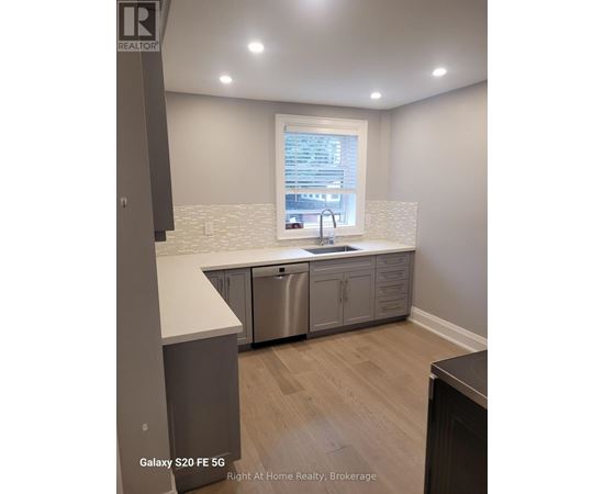 A kitchen with a stainless steel dishwasher and a window showing a cityscape.