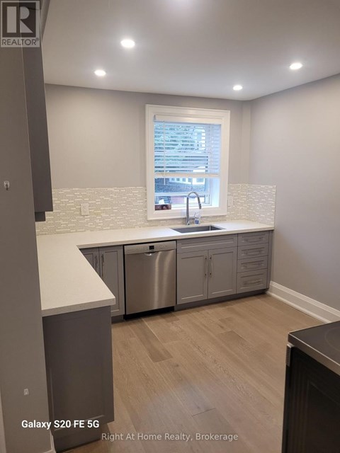 A kitchen with a stainless steel dishwasher and a window showing a cityscape.
