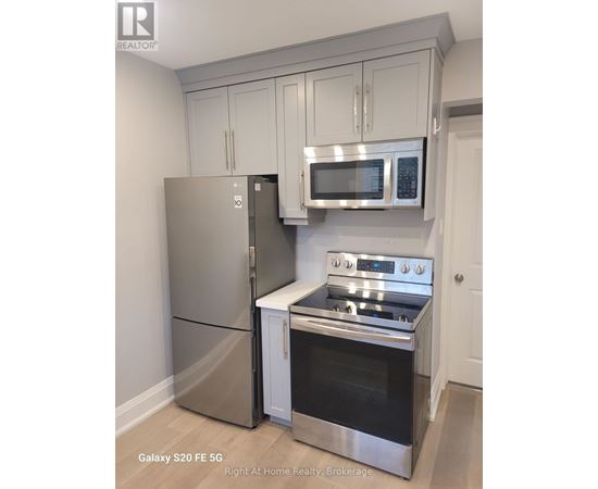 A kitchen with a stainless steel refrigerator, microwave, and oven.