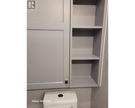 A white cabinet with a toilet in front of it.