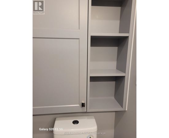 A white cabinet with a toilet in front of it.