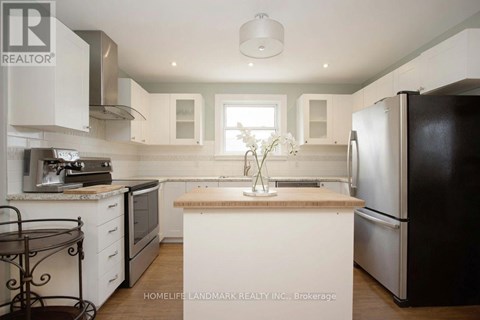 A kitchen with a black fridge, white cabinets and a wooden island.