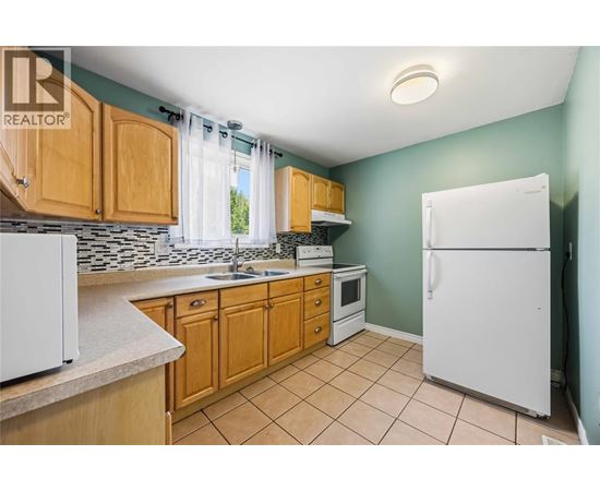 A kitchen with white appliances and wooden cabinets.