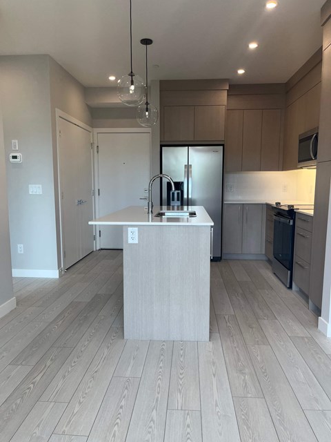 A kitchen with a wooden floor and a white island in the middle.