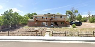 A brown house with a fence in front of it.