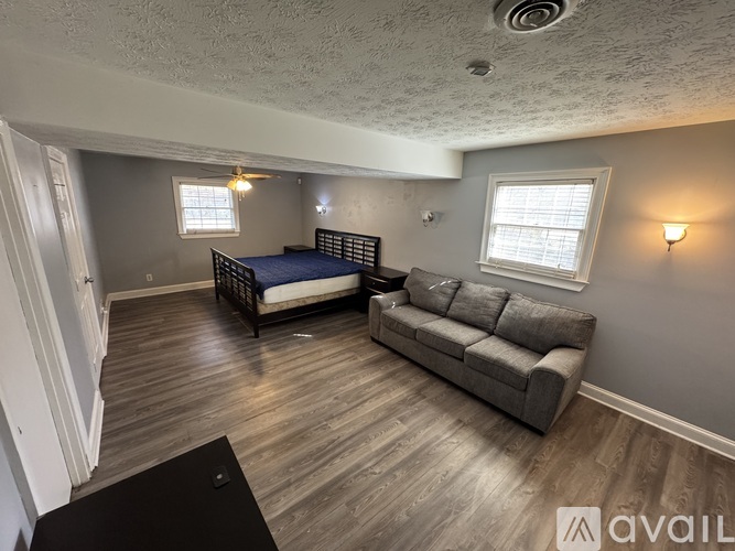 A bedroom with a bed, couch, and a window.