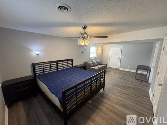 A bedroom with a bed, a couch, and a ceiling fan.