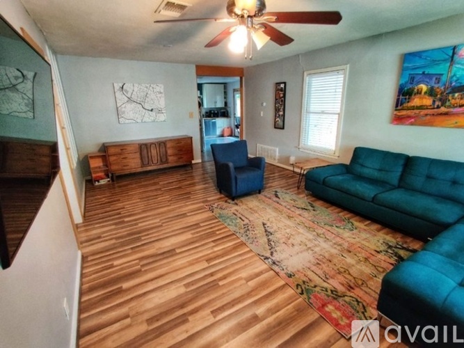 A living room with a blue couch and a rug.