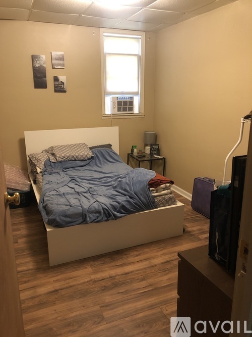 A bedroom with a bed, nightstand, and a window.