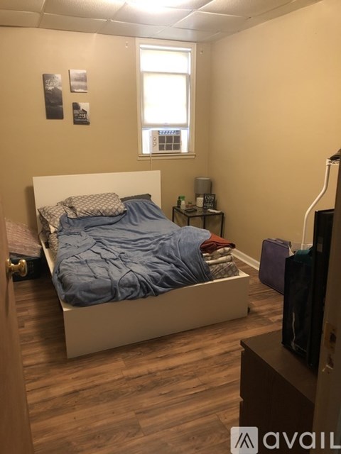 A bedroom with a bed, nightstand, and a window.