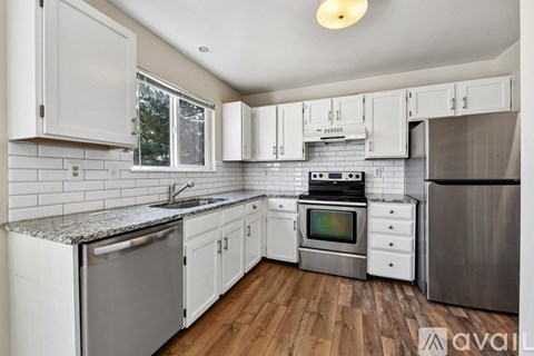 A kitchen with white cabinets and a wooden floor.