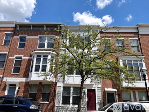A tree in front of a red brick building with a white window.