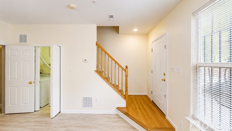 A white interior with a wooden staircase.