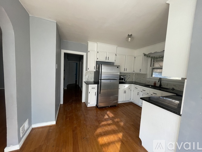 A kitchen with wooden floors and white cabinets.