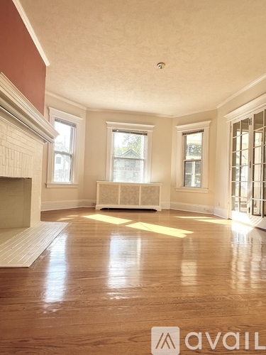 A large empty room with wood floors and a fireplace.