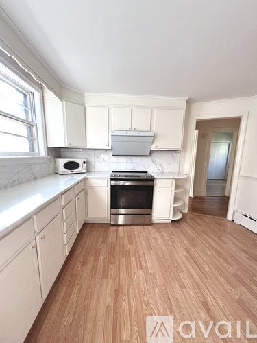 A kitchen with white cabinets and a wooden floor.