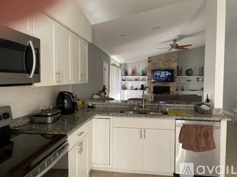 A kitchen with white cabinets and a black microwave.