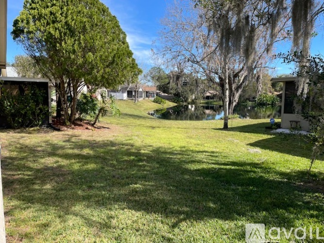 A grassy backyard with a tree and a house in the background.
