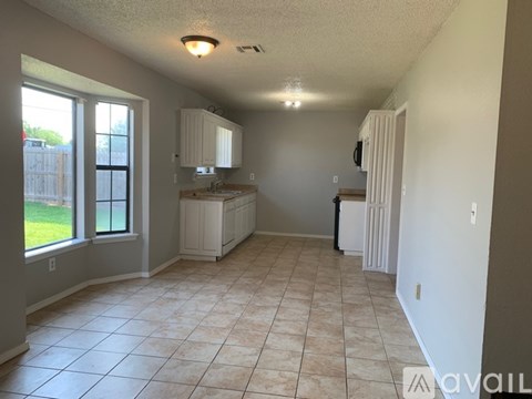 A kitchen area with white cabinets and a tiled floor.