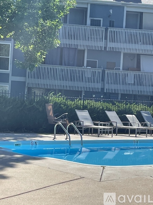 A pool with a slide and chairs in front of a building.