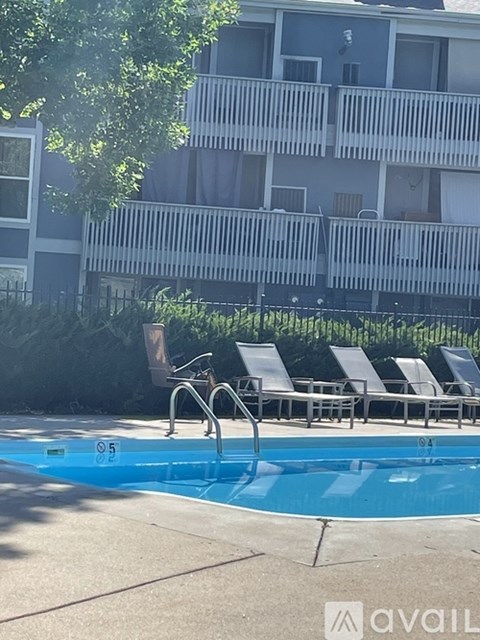 A pool with a slide and chairs in front of a building.