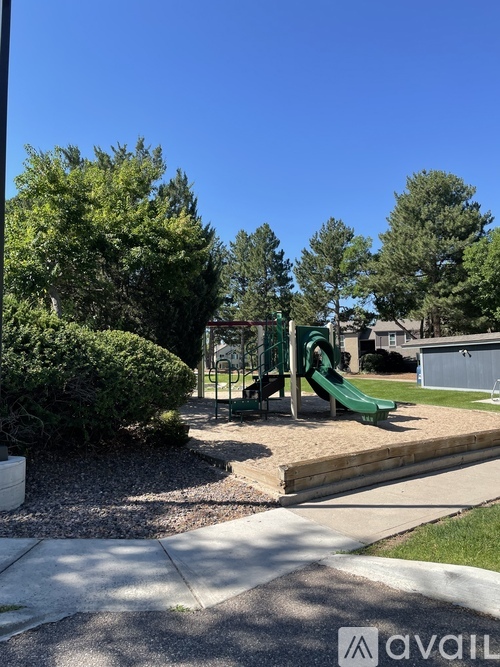 A playground with a green slide and a wooden structure.
