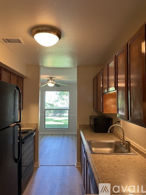A kitchen with a black fridge and wooden cabinets.