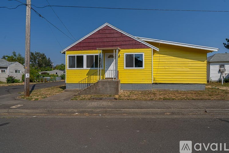 A yellow house with a red roof is situated on a street.